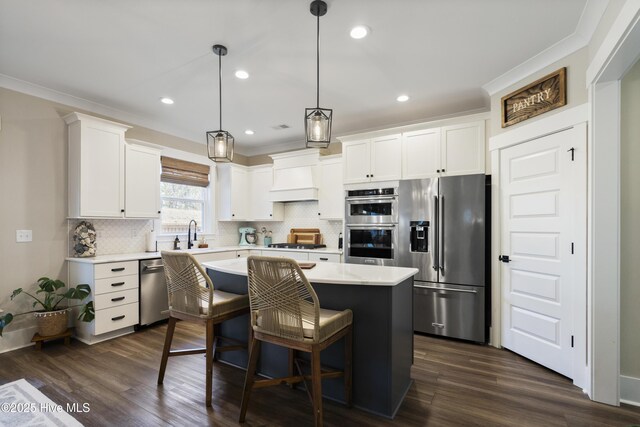 kitchen featuring a center island, pendant lighting, stainless steel appliances, light countertops, and white cabinets