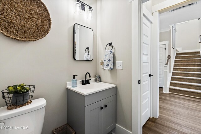 foyer entrance featuring dark wood finished floors, visible vents, stairway, ornamental molding, and baseboards