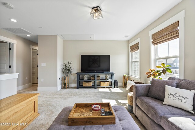 living area featuring attic access, visible vents, light carpet, and baseboards