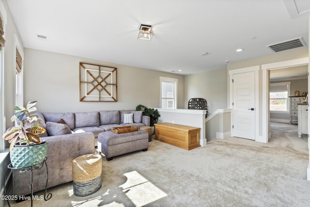 living area with light colored carpet, visible vents, and baseboards