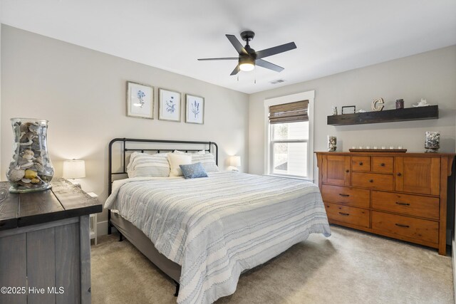 office space with light carpet, a ceiling fan, visible vents, and baseboards