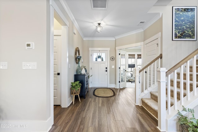 entrance foyer featuring dark wood finished floors, visible vents, crown molding, and stairs