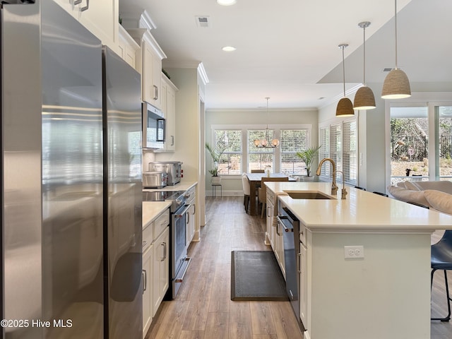 kitchen featuring stainless steel appliances, ornamental molding, a breakfast bar area, and a sink