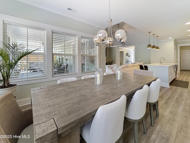 dining space featuring crown molding, a notable chandelier, visible vents, light wood-style flooring, and baseboards