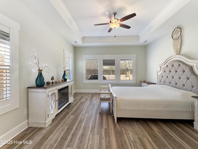 bedroom featuring crown molding, a raised ceiling, and wood finished floors