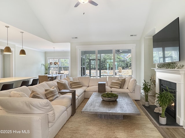 living area with vaulted ceiling, a fireplace, wood finished floors, and visible vents