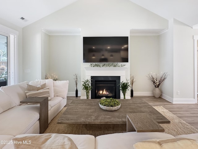 living area with a warm lit fireplace, lofted ceiling, wood finished floors, visible vents, and baseboards