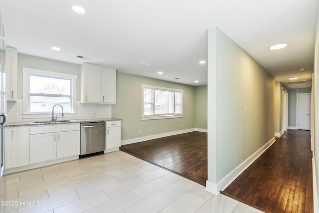 kitchen featuring a sink, light stone counters, decorative backsplash, and stainless steel dishwasher