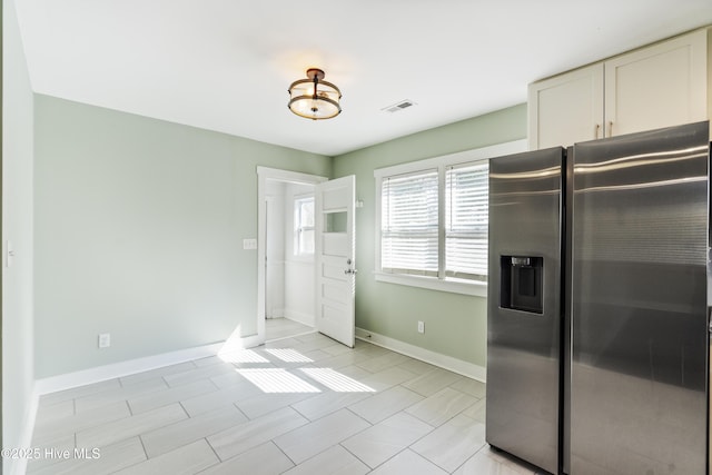 kitchen with baseboards, visible vents, and stainless steel refrigerator with ice dispenser