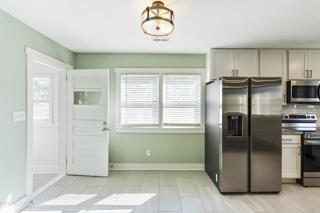 kitchen featuring stainless steel appliances, tasteful backsplash, visible vents, gray cabinetry, and baseboards