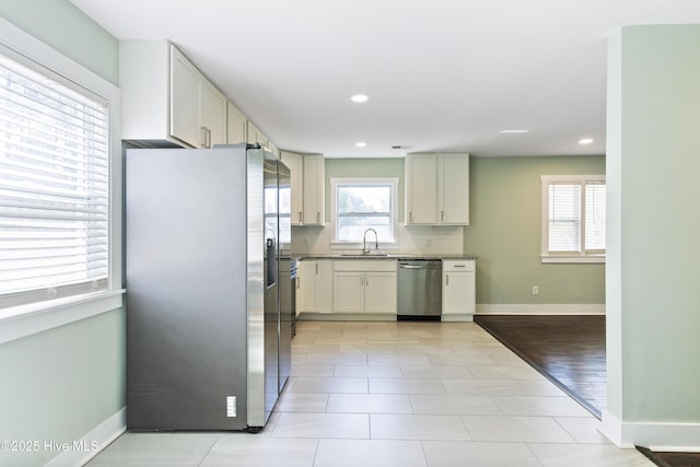 kitchen featuring appliances with stainless steel finishes, baseboards, a sink, and decorative backsplash