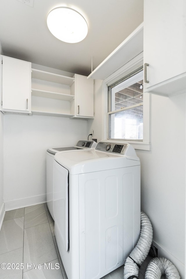 clothes washing area with cabinet space, independent washer and dryer, baseboards, and light tile patterned flooring