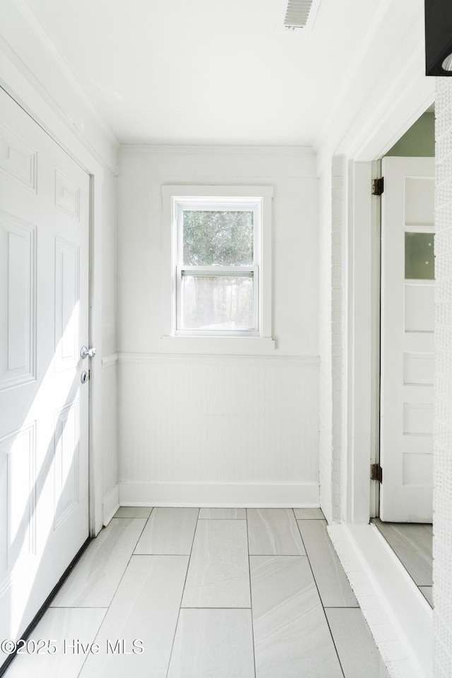 unfurnished room with wainscoting, visible vents, and light tile patterned floors