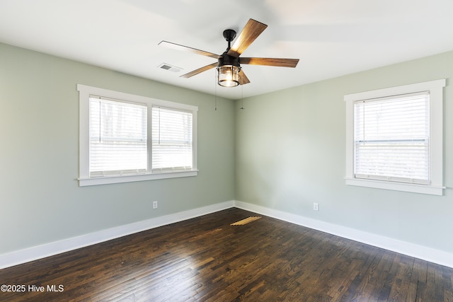 empty room featuring a ceiling fan, baseboards, visible vents, and dark wood-type flooring