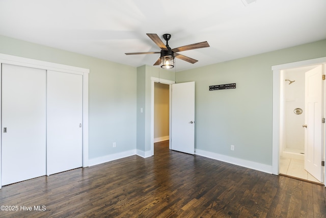 unfurnished bedroom featuring baseboards, dark wood finished floors, a ceiling fan, connected bathroom, and a closet