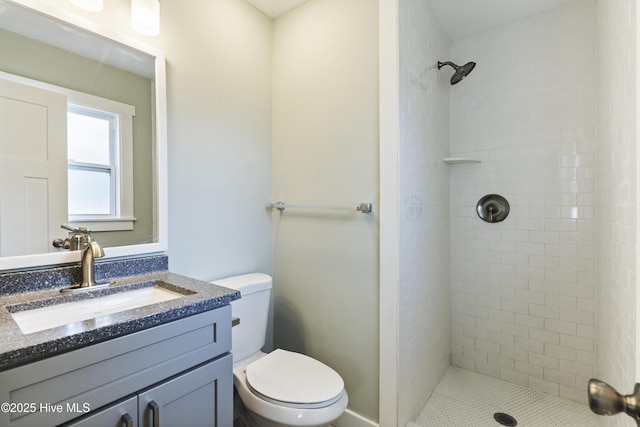 full bath with a tile shower, vanity, and toilet