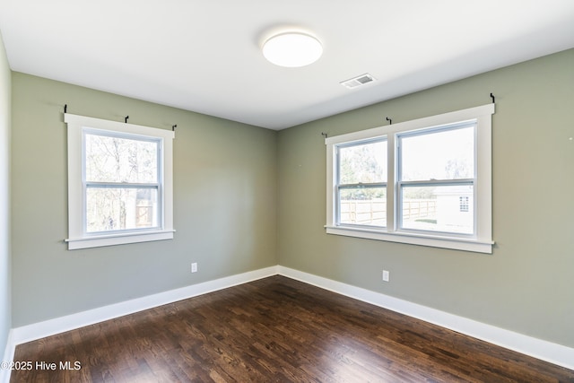 spare room with visible vents, dark wood finished floors, and baseboards