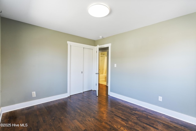 unfurnished bedroom with baseboards, dark wood finished floors, and a closet