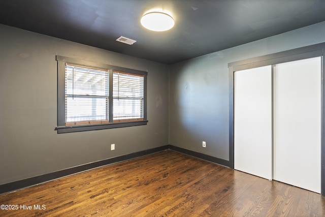 interior space with dark wood-type flooring, visible vents, and baseboards