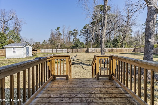 wooden terrace featuring a storage unit, a lawn, an outdoor structure, and a fenced backyard