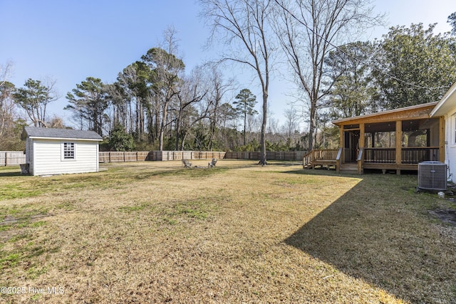 view of yard featuring a storage shed, a deck, cooling unit, a fenced backyard, and an outdoor structure