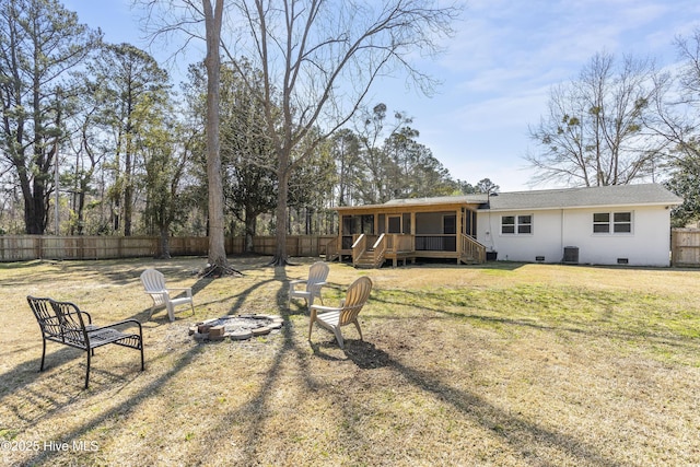 rear view of property with a lawn, crawl space, fence, a deck, and a fire pit