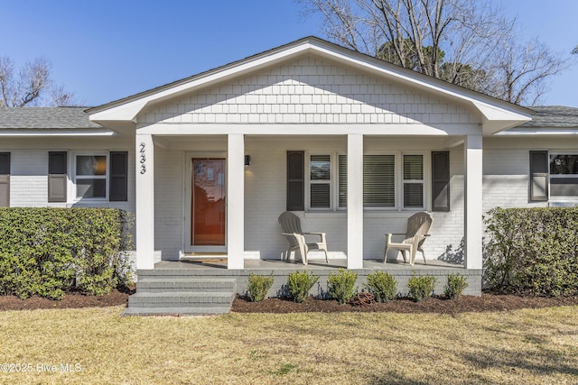 view of front facade featuring a porch, brick siding, and a front lawn