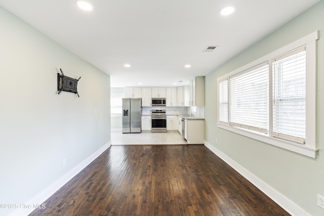 kitchen with stainless steel appliances, visible vents, baseboards, and white cabinetry