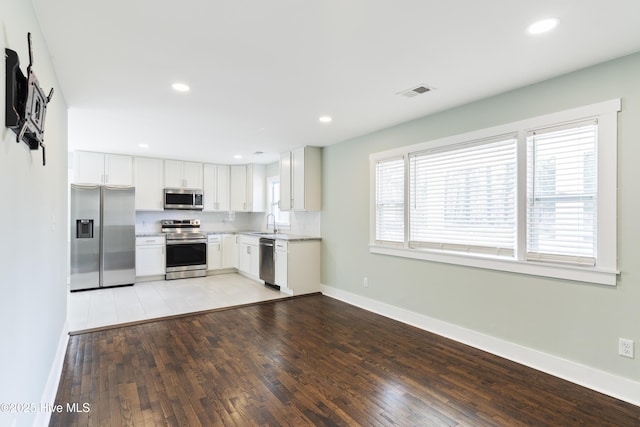 kitchen featuring stainless steel appliances, light wood-type flooring, visible vents, and baseboards