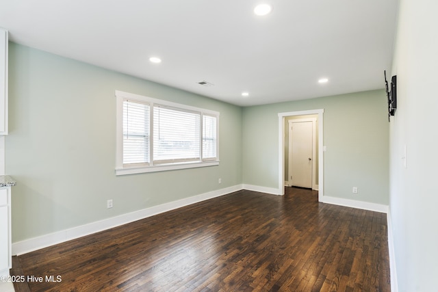 unfurnished room with dark wood-type flooring, recessed lighting, visible vents, and baseboards