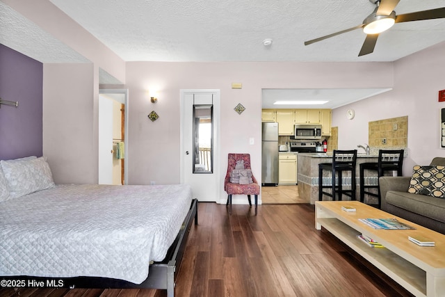 bedroom featuring a textured ceiling, wood finished floors, and freestanding refrigerator