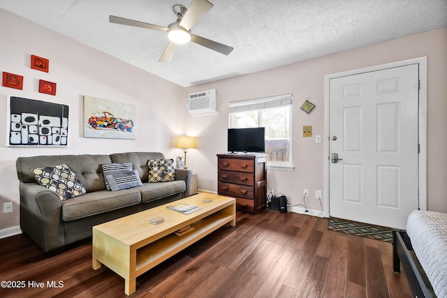 living room with baseboards, ceiling fan, dark wood-style flooring, a textured ceiling, and a wall mounted AC