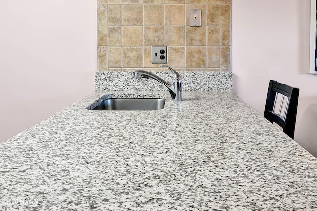 interior details with tasteful backsplash, light stone counters, and a sink