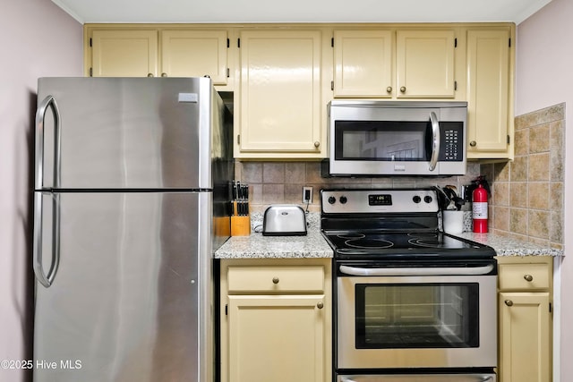 kitchen with stainless steel appliances, tasteful backsplash, and light stone countertops