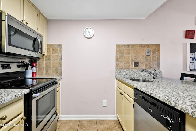 kitchen featuring tasteful backsplash, light stone countertops, stainless steel appliances, a sink, and light tile patterned flooring