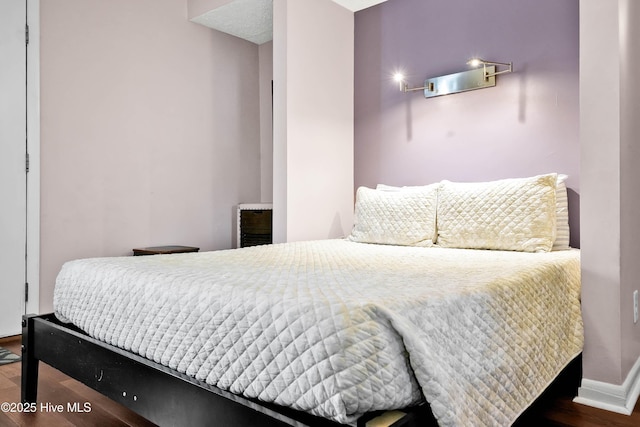 bedroom with dark wood-style flooring and baseboards