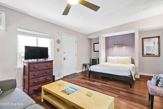 bedroom featuring a textured ceiling, wood finished floors, a ceiling fan, and baseboards