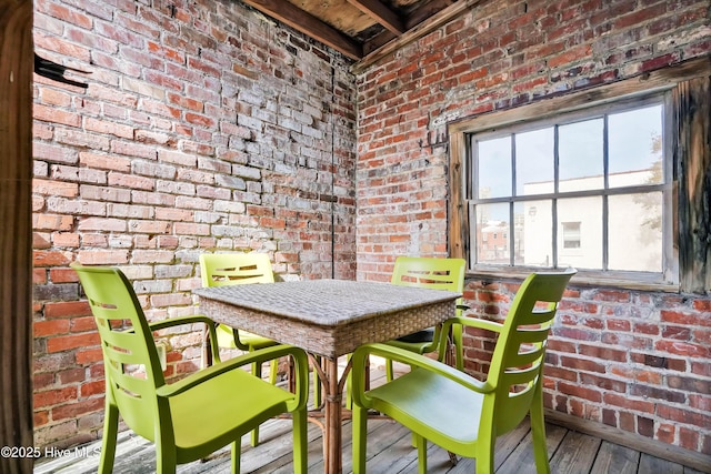 dining room featuring brick wall and wood-type flooring