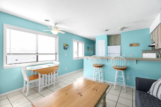 1618 Canal Dr Unit C-44, Carolina Beach, NC 28428 - kitchen featuring freestanding refrigerator, exhaust hood, a kitchen breakfast bar, a peninsula, and ceiling fan
