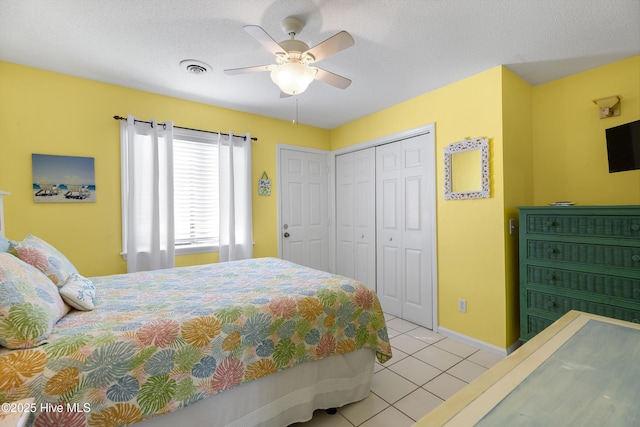 bedroom with a textured ceiling, visible vents, a closet, and light tile patterned flooring