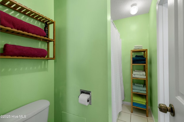 full bath with baseboards, toilet, curtained shower, tile patterned flooring, and a textured ceiling