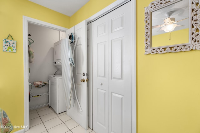 clothes washing area with a ceiling fan, stacked washer and clothes dryer, light tile patterned floors, and laundry area