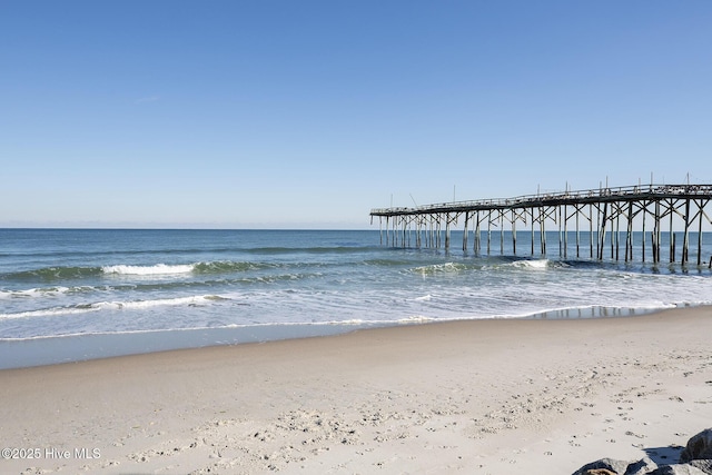 view of dock featuring a pier, a view of the beach, and a water view