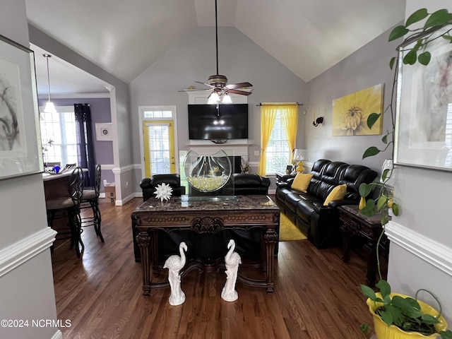 living room featuring baseboards, dark wood finished floors, a ceiling fan, a glass covered fireplace, and vaulted ceiling