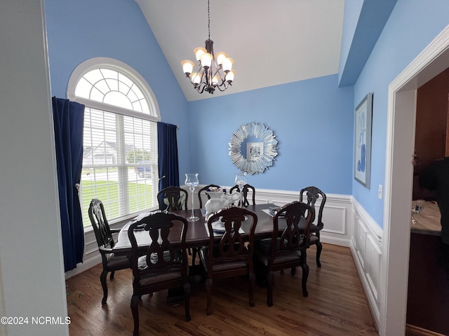 dining area featuring an inviting chandelier, vaulted ceiling, wood finished floors, and wainscoting