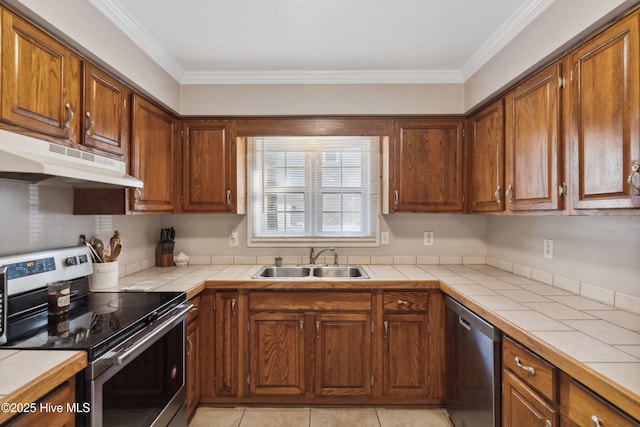 kitchen with tile counters, appliances with stainless steel finishes, brown cabinets, under cabinet range hood, and a sink