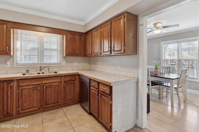 kitchen with brown cabinets, tile countertops, stainless steel dishwasher, ornamental molding, and a sink