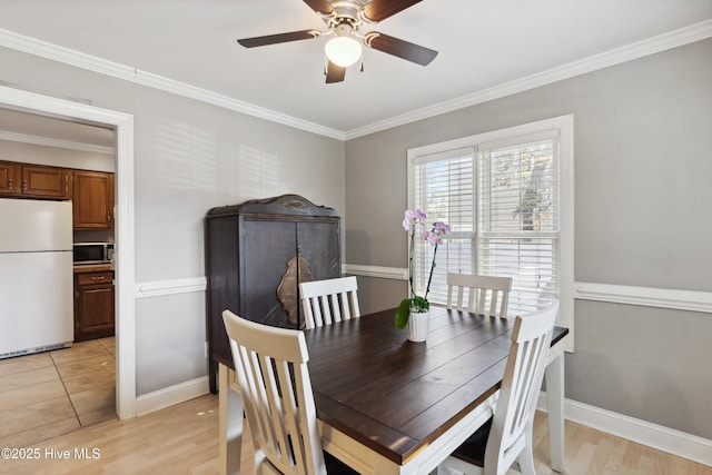 dining area featuring light wood finished floors, ceiling fan, baseboards, and crown molding