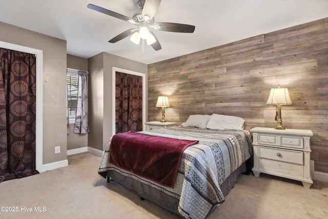 bedroom featuring ceiling fan, light colored carpet, wood walls, baseboards, and a closet