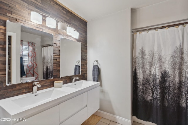 full bathroom with double vanity, tile patterned flooring, baseboards, and a sink